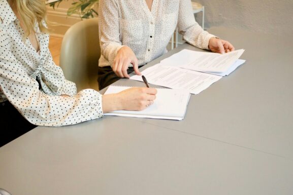Two people at a table reviewing and signing documents during a consultation